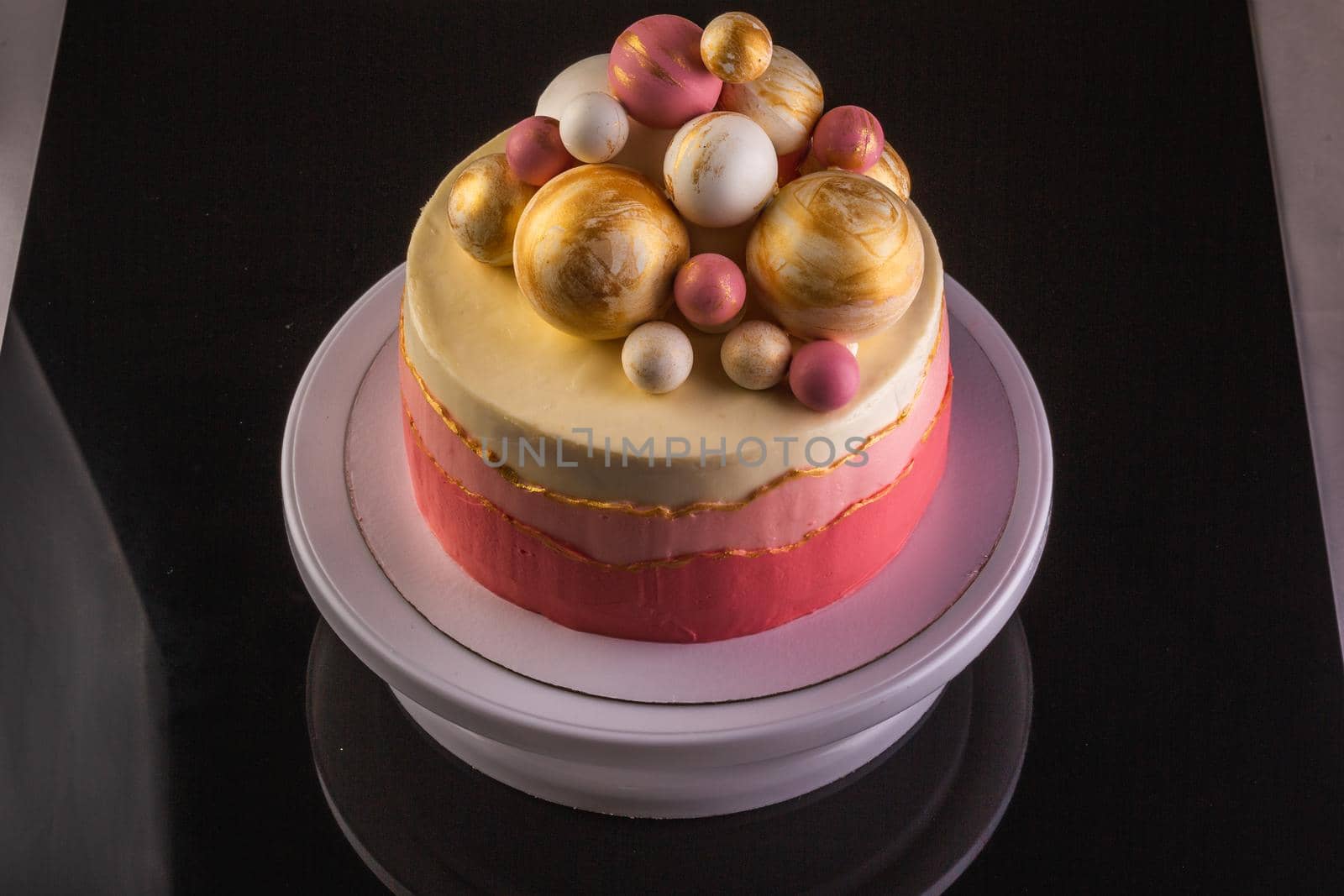 Chocolate layered cake with ganache cream and pink confiture. Decorated with purple and gold chocolate spheres.