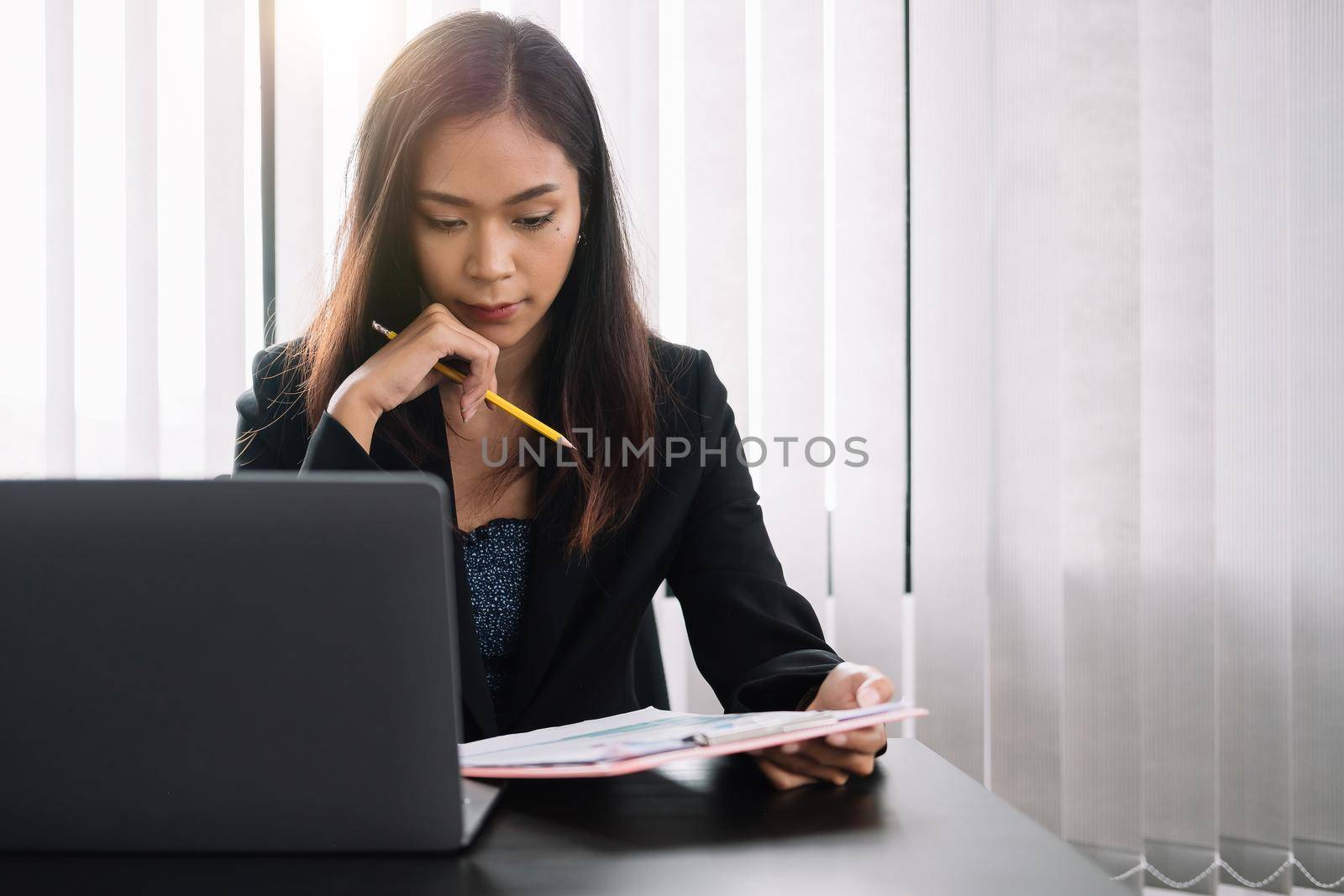 Businesswoman analyst financial document report while using laptop computer.