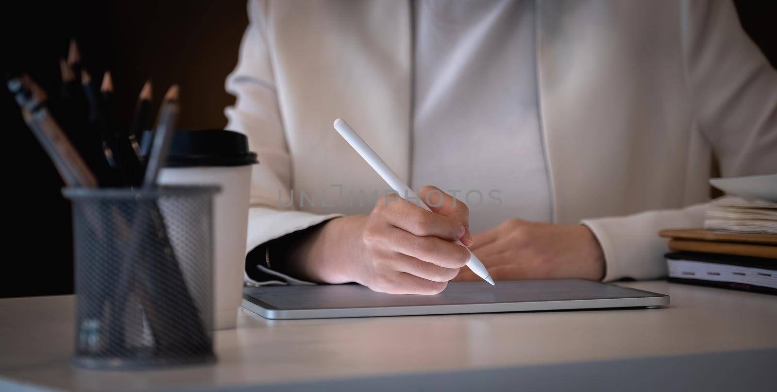 Close up businesswoman holds pen stylus drawing on digital tablet on workplace by nateemee