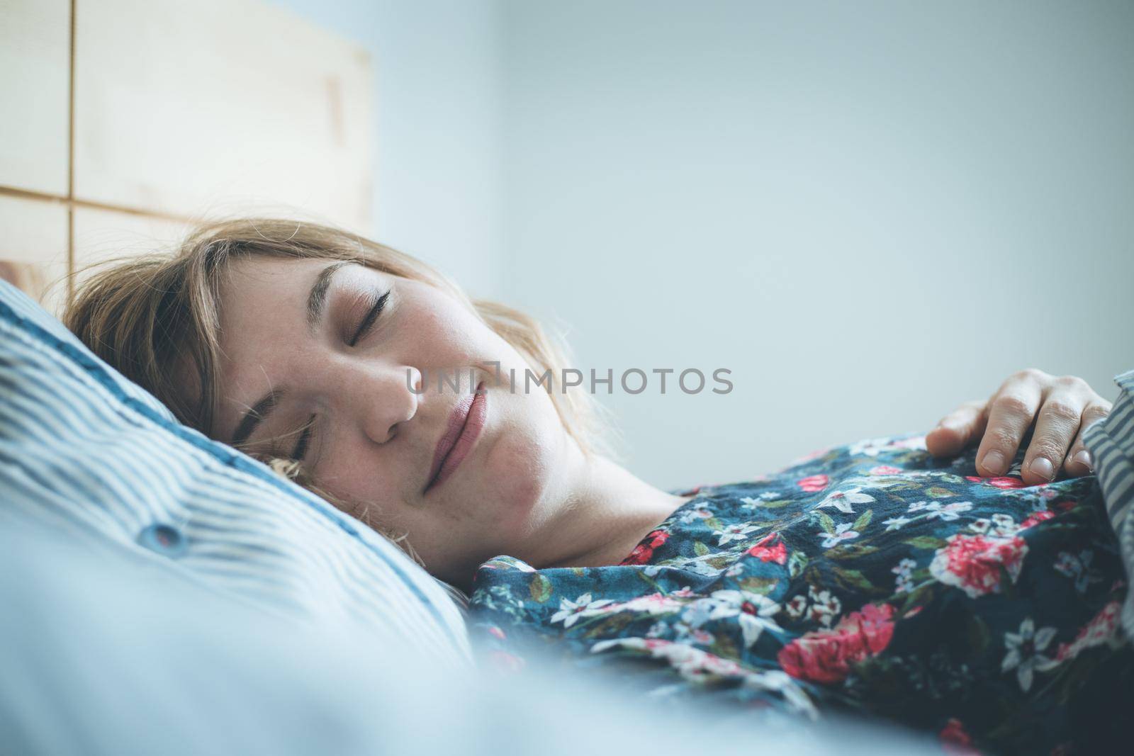 Young woman sleeping peacefully in her bedroom, day