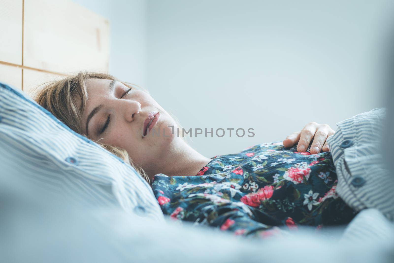 Young woman sleeping peacefully in her bedroom, day