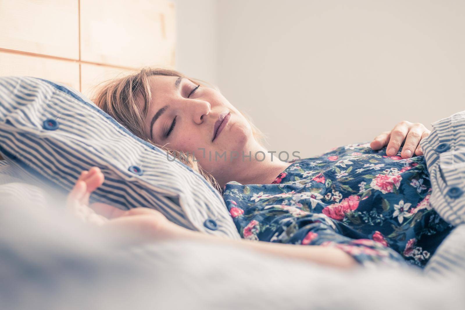 Young woman sleeping peacefully in her bedroom, day
