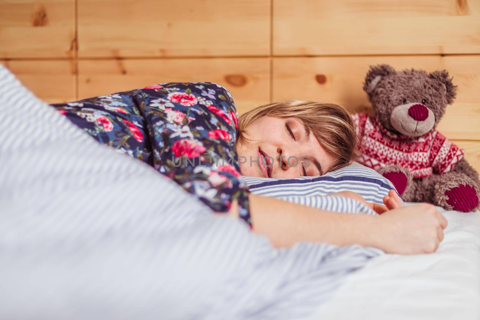 Young woman is sleeping peacefully with her teddy bear in her bedroom