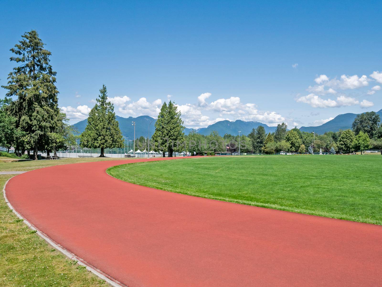 Red jogging track of recreational stadium on bright sunny day in Vancouver, Canada.