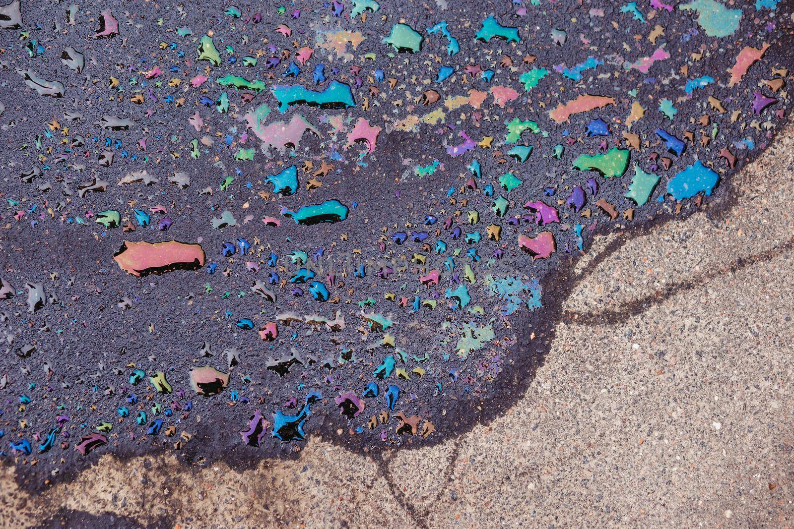 Abstract background, colorful stain of gas or oil on the asphalt caused by a leak from a car. Environmental pollution concept.