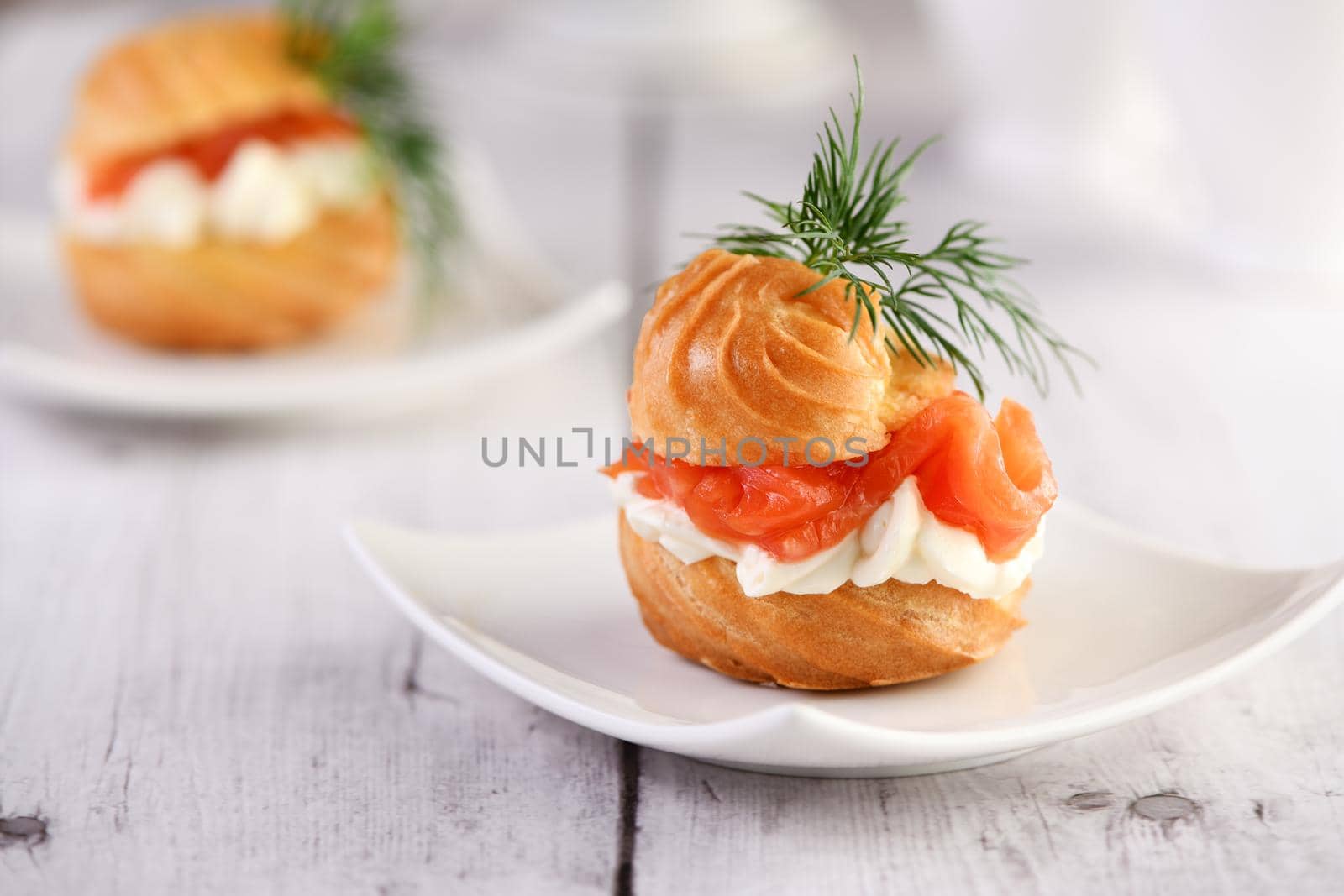 Profiteroles stuffed with cream cheese and salmon, decorated with a sprig of dill. Close-up 