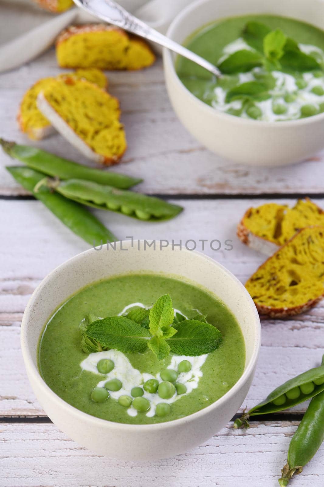 Chilled soup puree of green peas,  seasoned with green onion, mint and crunchy  toasted diced rusk bread  