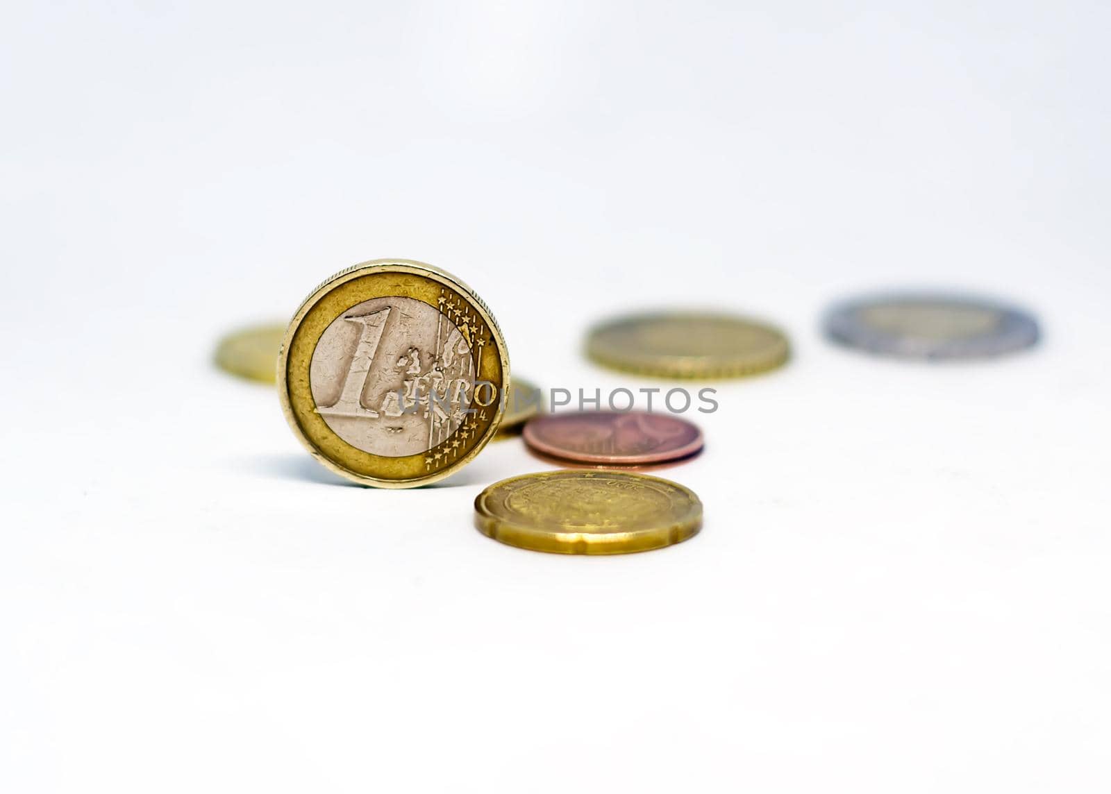 One euro coin standing together with various scattered coins isolated on a white background. Economics and finance. European union currency