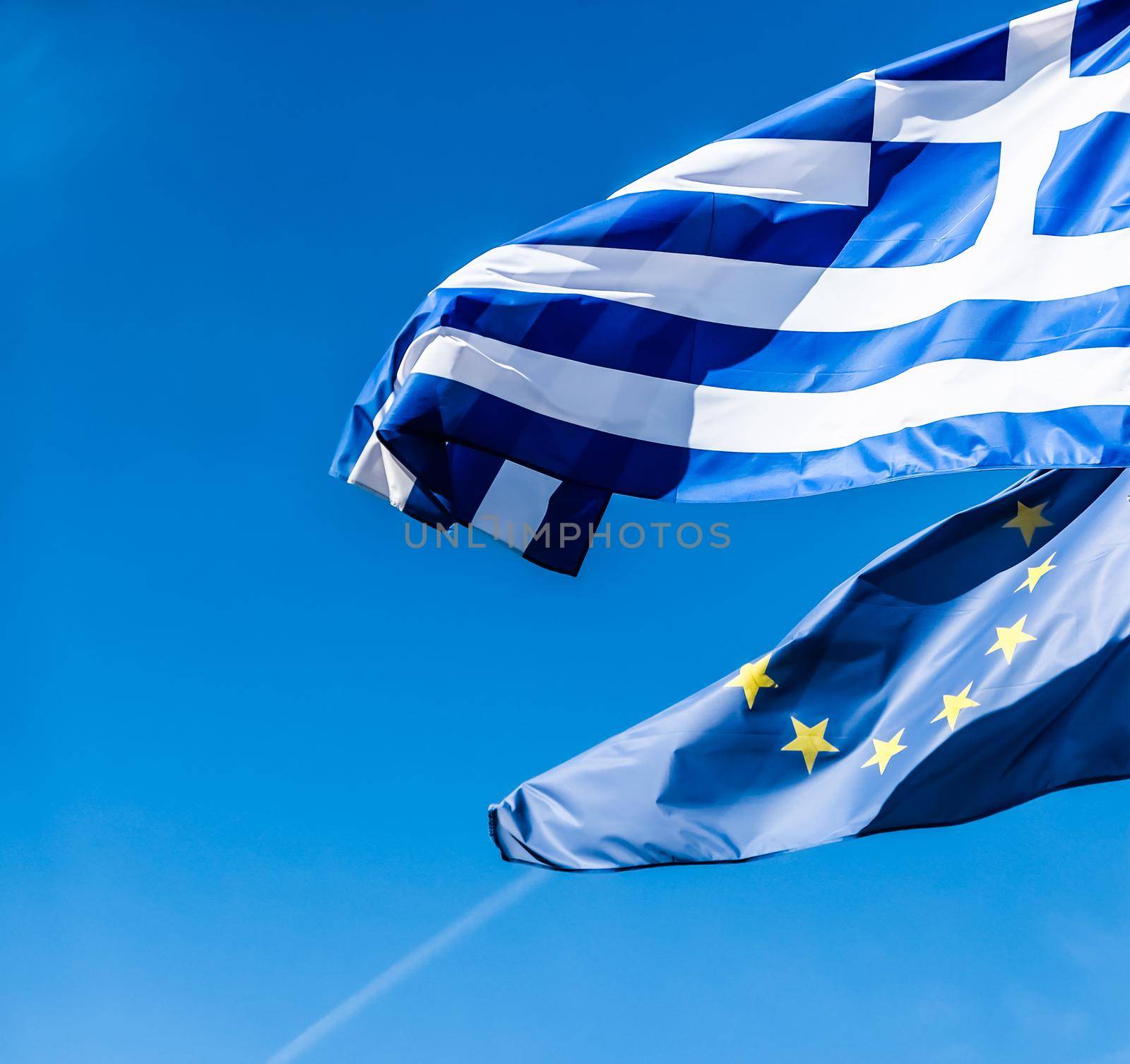 Flags of Greece and European Union on blue sky background, politics of Europe by Anneleven