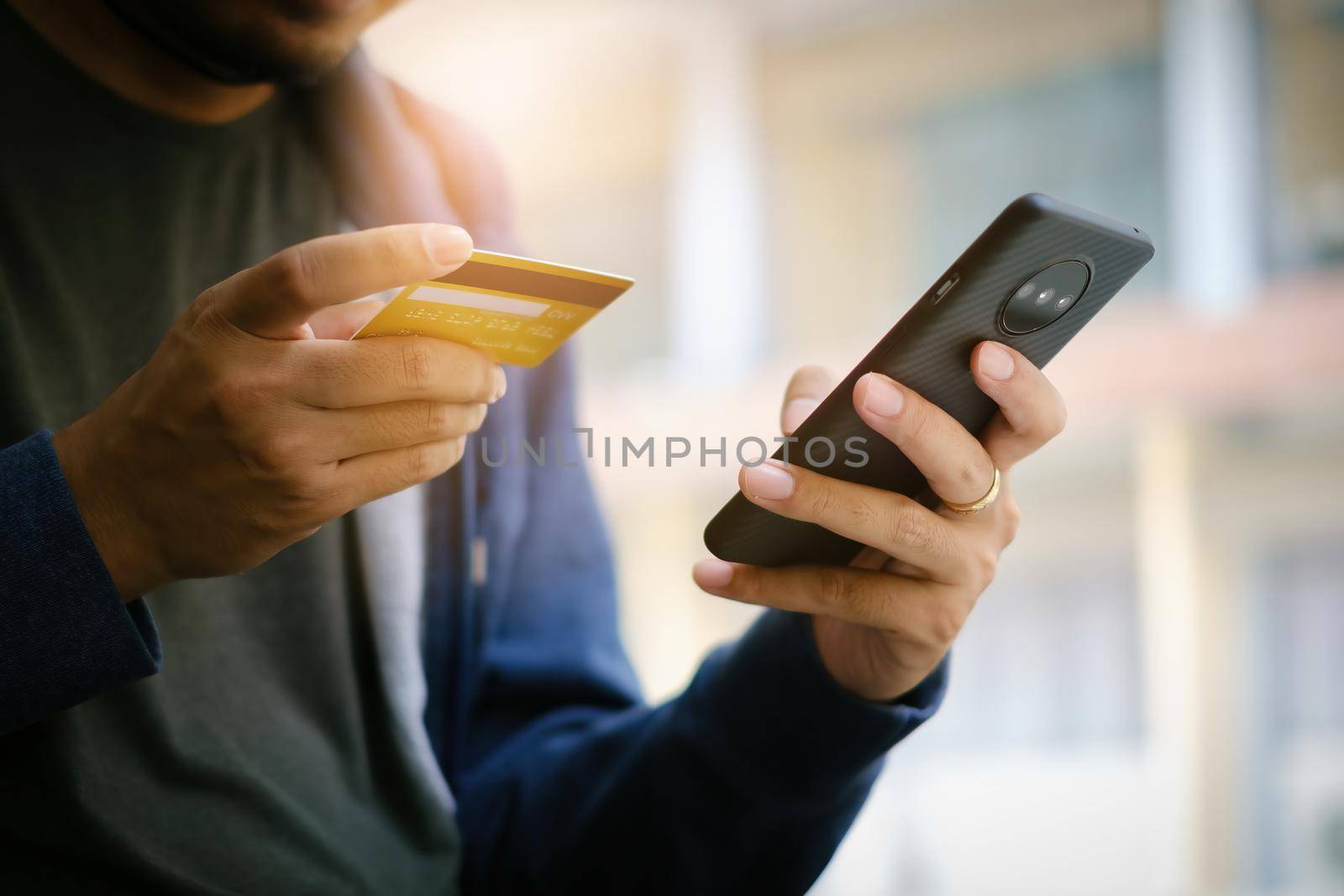 A young man makes a purchase on the Internet on the smartphone with credit card. Shopping online concept.. by itchaznong