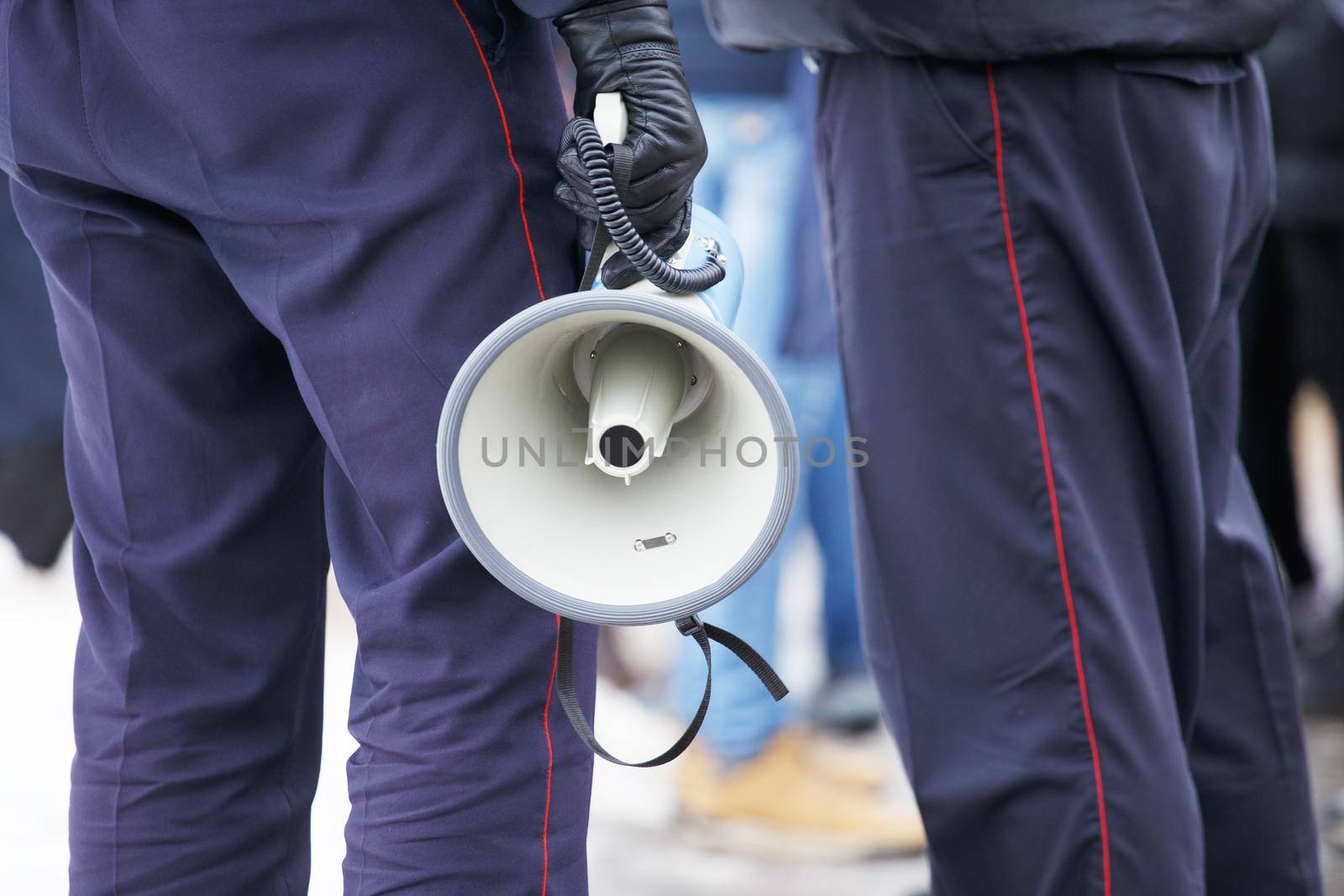 police officer holding loudspeaker megaphone at daylight, close-up with selective focus