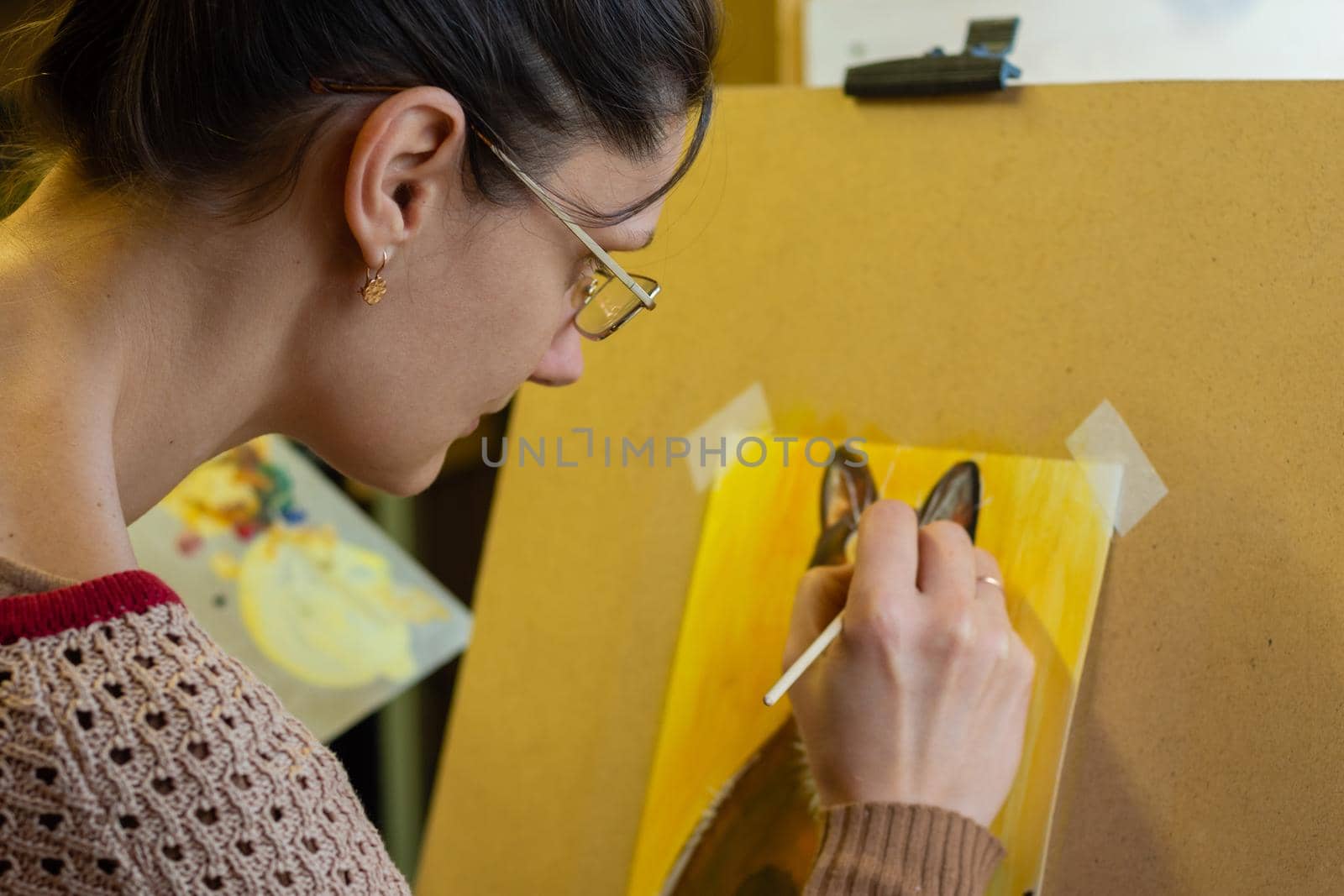 The artist draws a drawing on an easel, side view, close-up