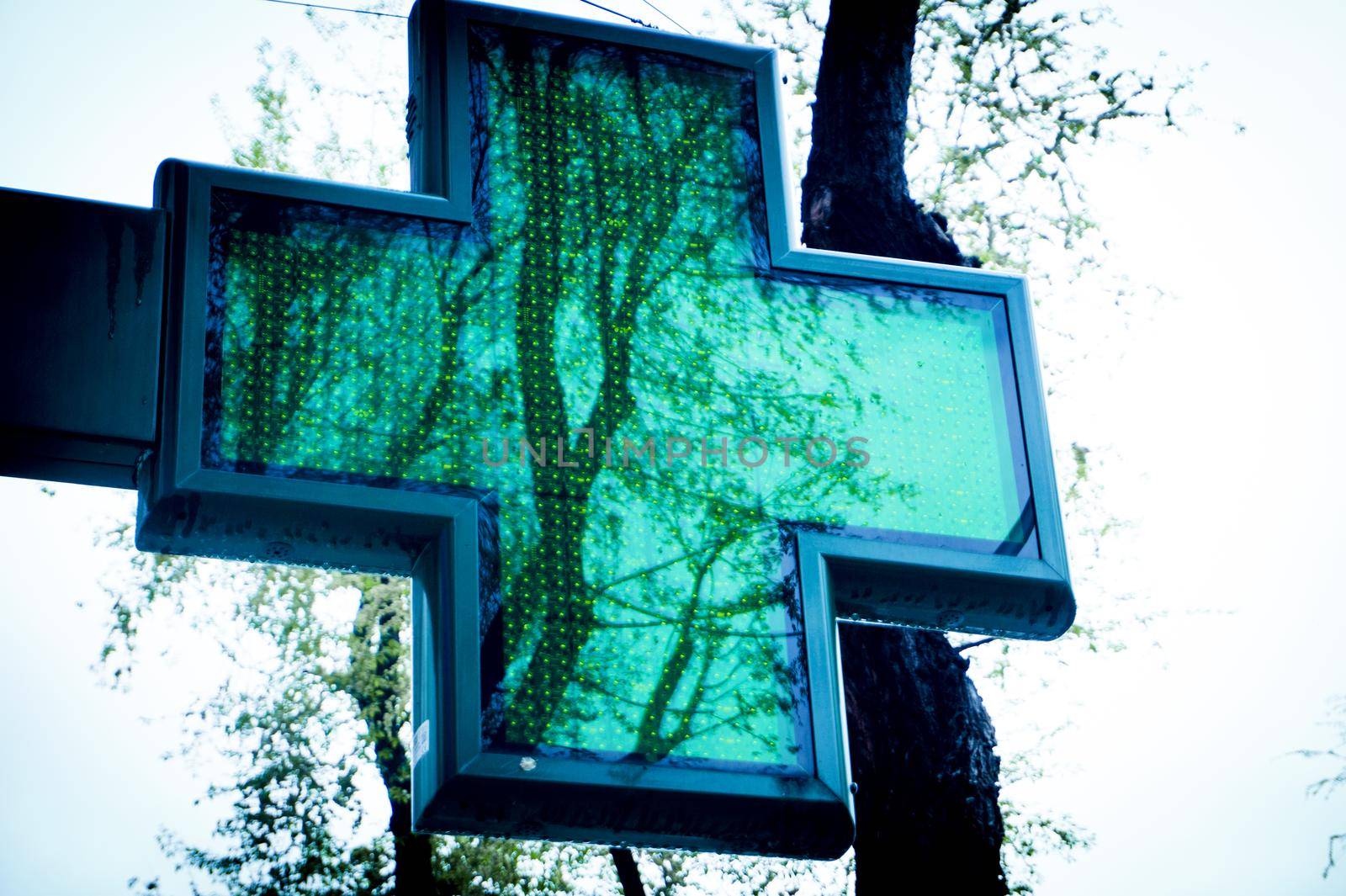 Green cross pharmacy symbol on blue sky background. No people