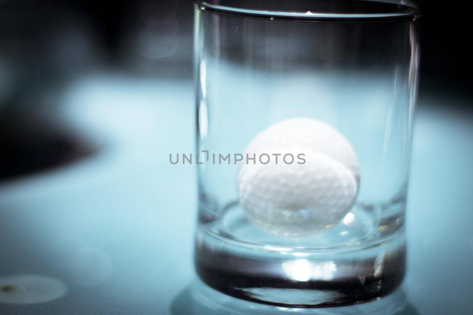 Golf ball inside a clear glass cup. No people