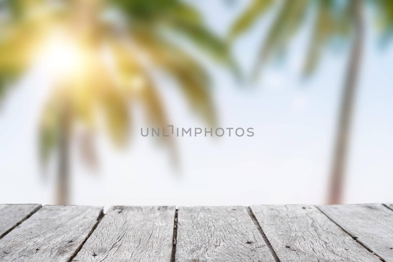 Selective focus of old wood table with blur beautiful beach with tropical palm tree for display your product.