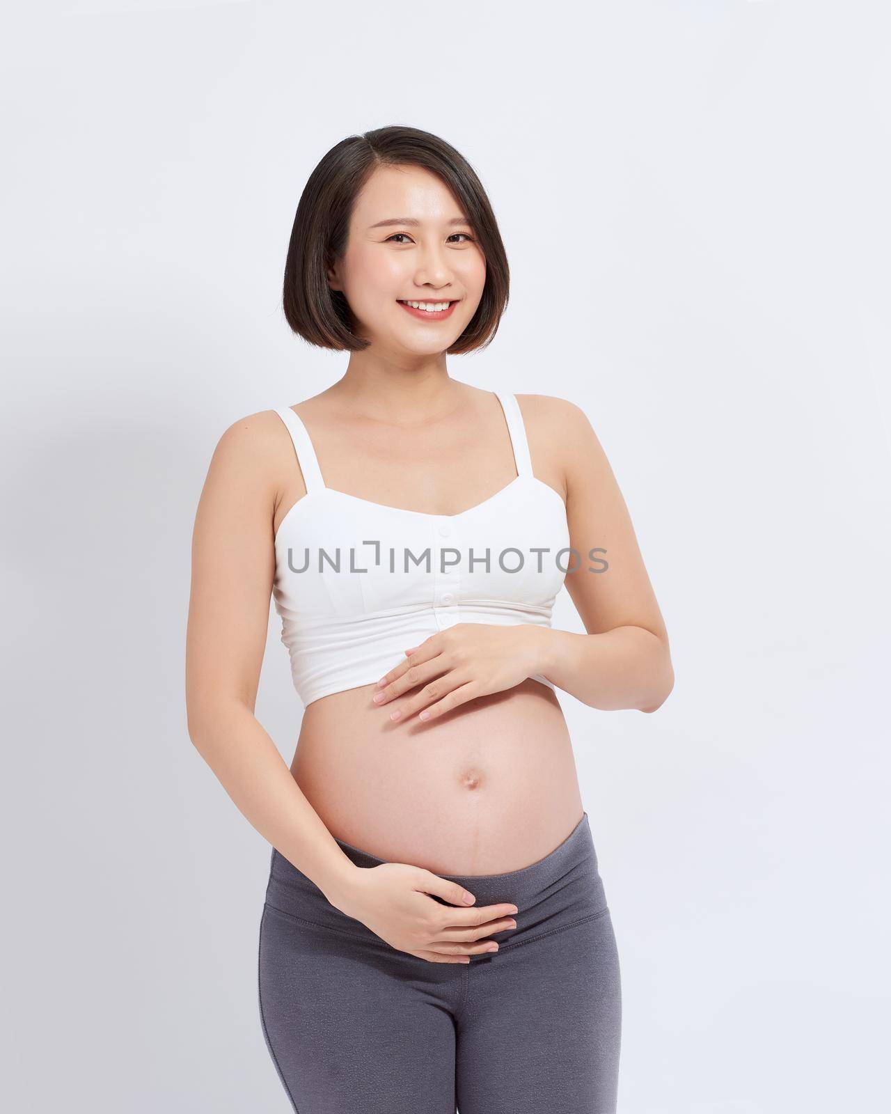 A beautiful Asian woman standing touching her belly. Pregnancy and expectation concept