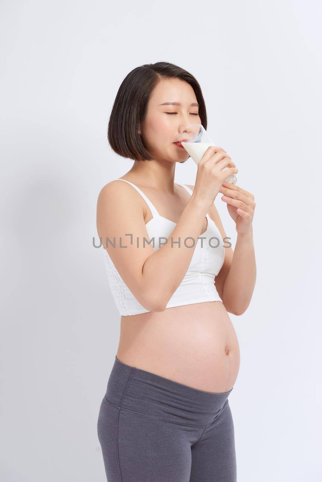 Pregnant woman drinking milk on the white background.