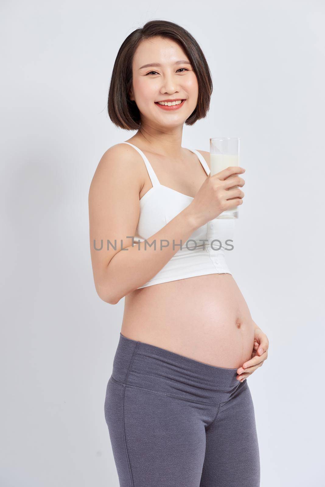 Pregnant woman holding glass of milk in her hand good healty, isolated on white background.