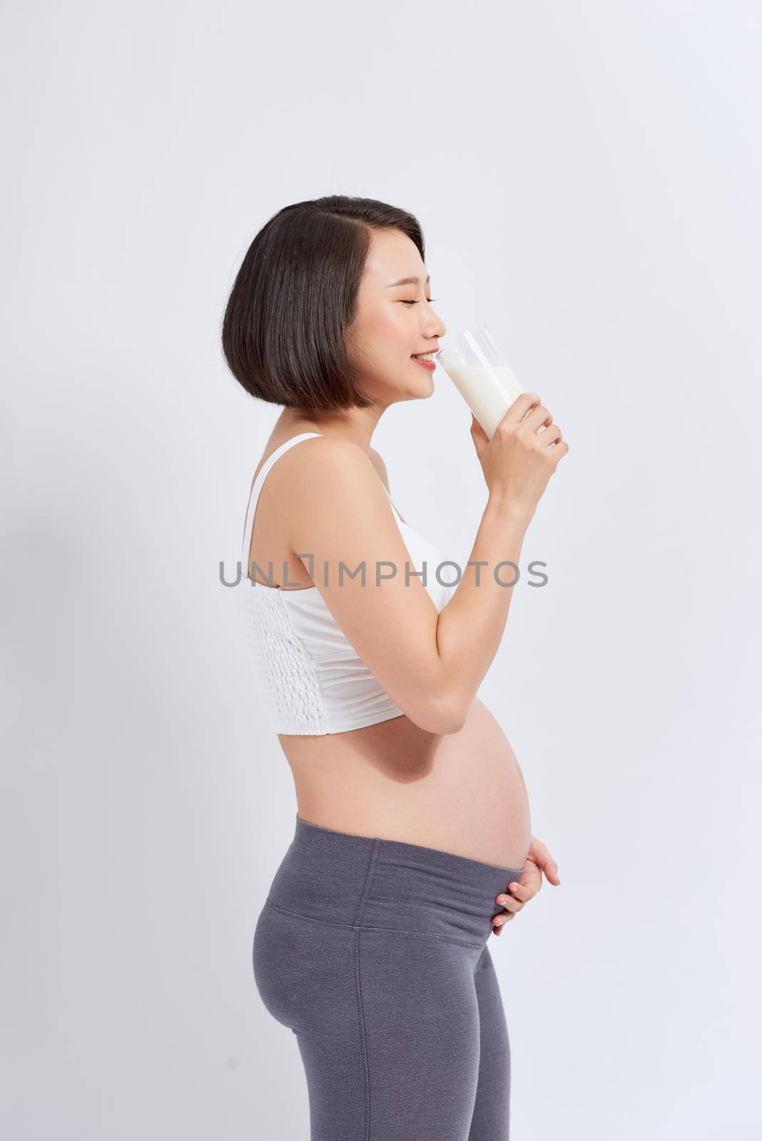 Pregnant woman drinking milk over white by makidotvn