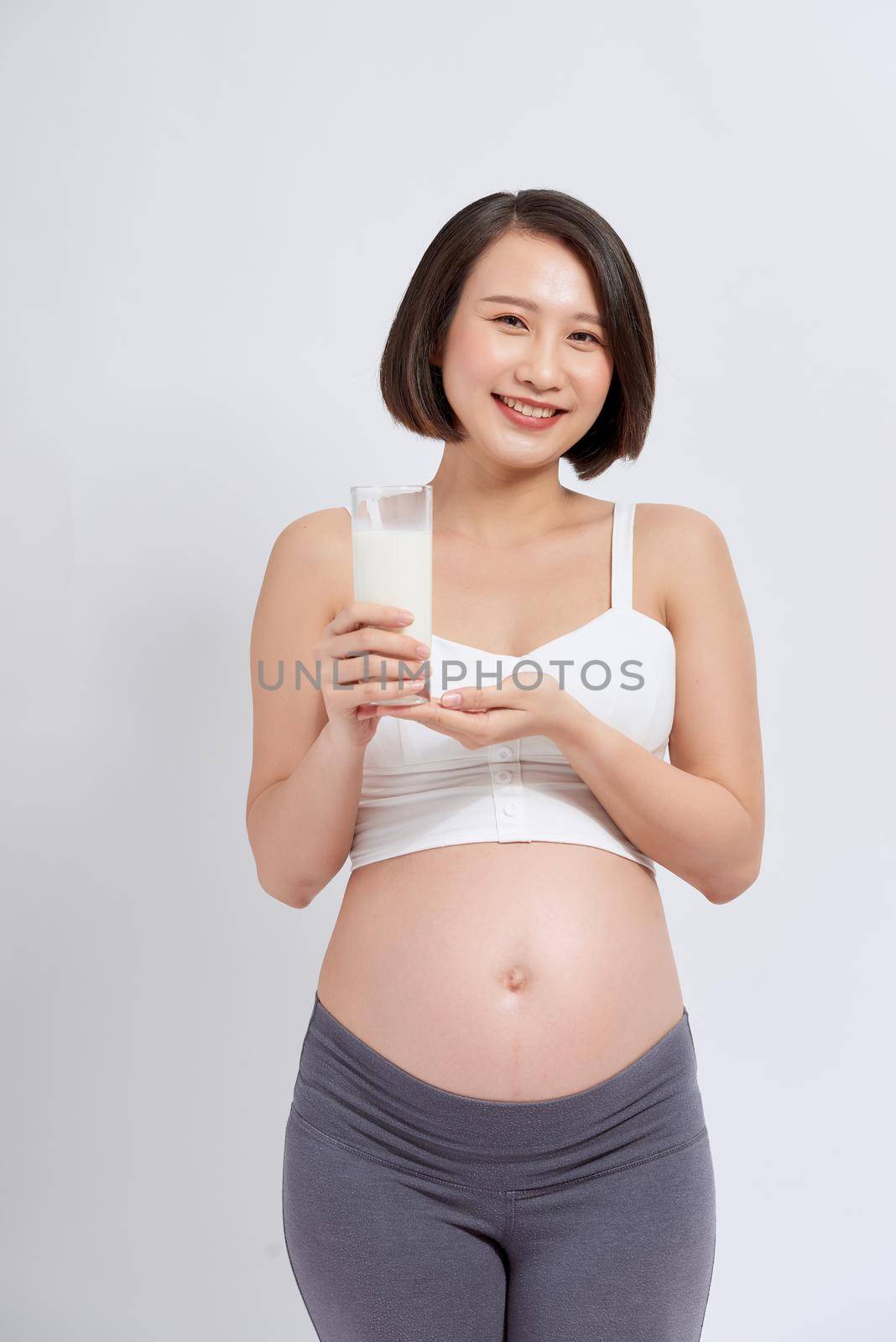Pregnant young asian woman with a glass of milk in hand.