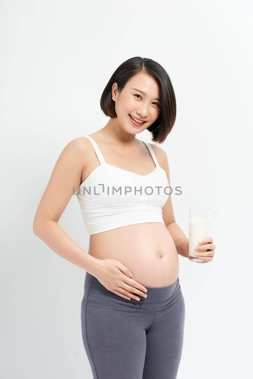 Pregnant woman drinking milk on the white background. by makidotvn