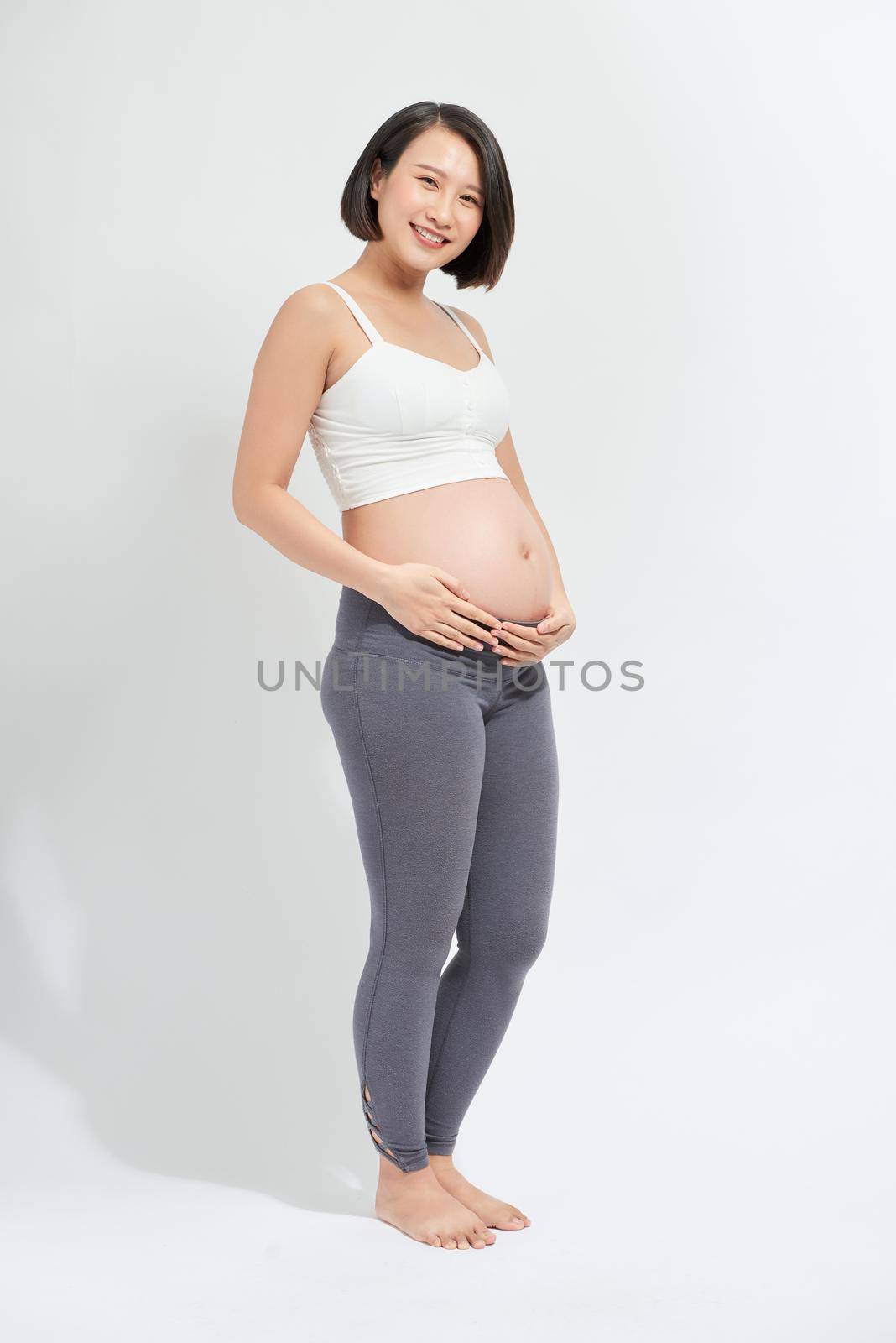 The young expecting mother holding baby in pregnant belly.