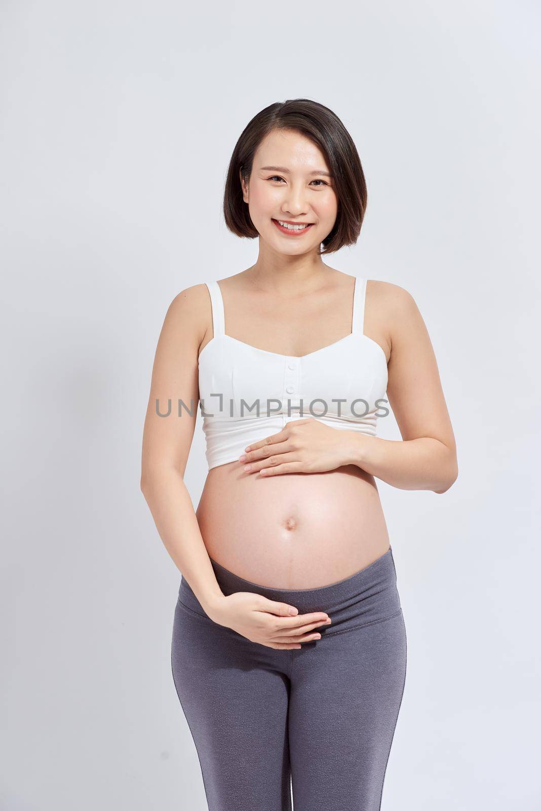 A beautiful Asian woman standing touching her belly. Pregnancy and expectation concept