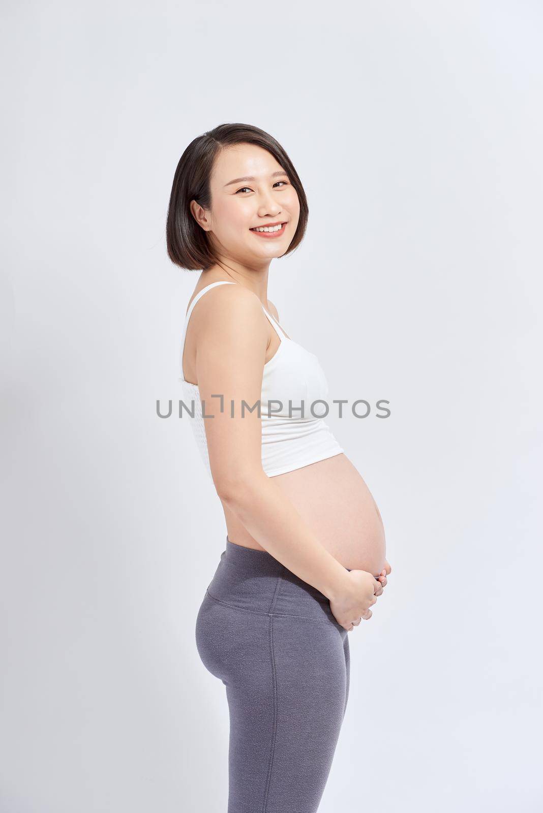 pregnant woman caressing her belly over white background