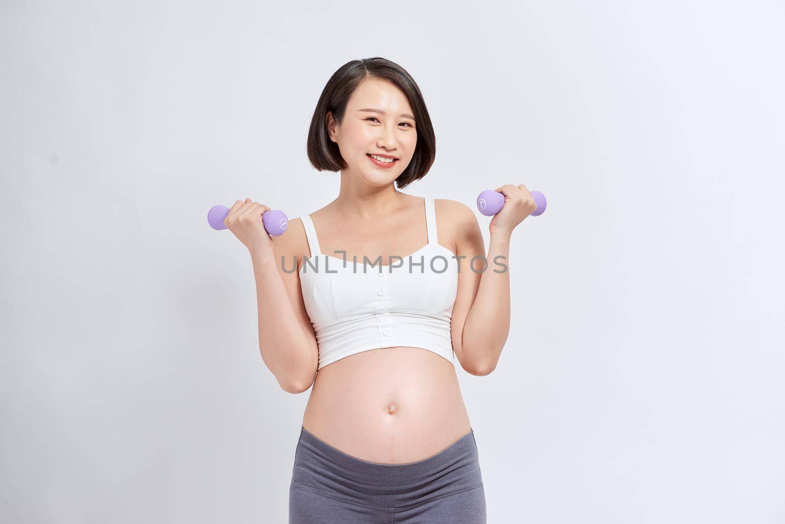 Sporty pregnant woman exercising with dumbbells