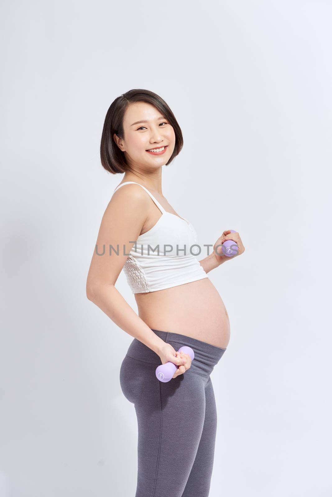 Asian pregnant woman do exercise, standing and lifting dumbbells, sportive pregnancy motherhood concept by makidotvn
