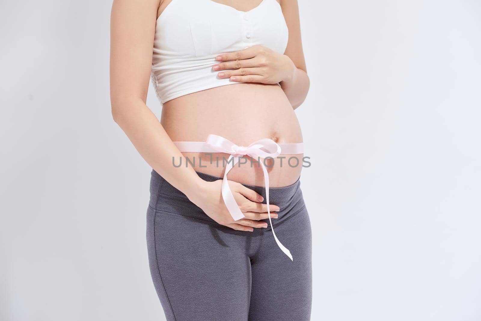 Pregnant belly with pink ribbon - isolated over a white background.