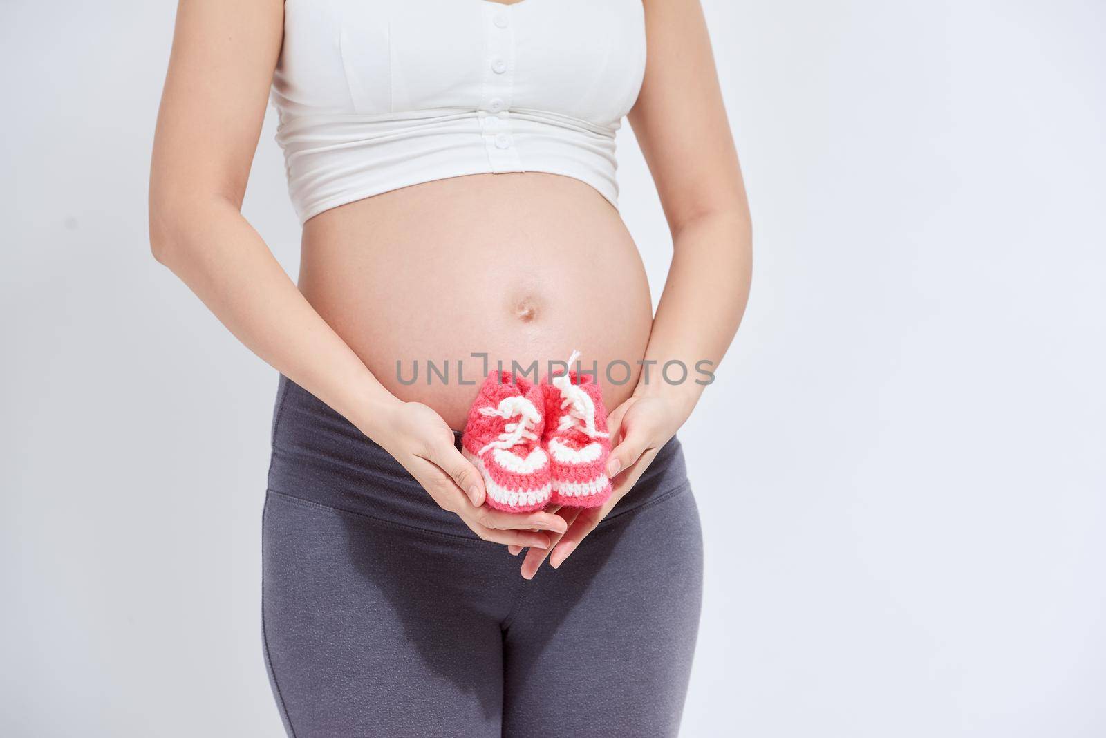 Small shoes for the unborn baby in the belly of pregnant woman