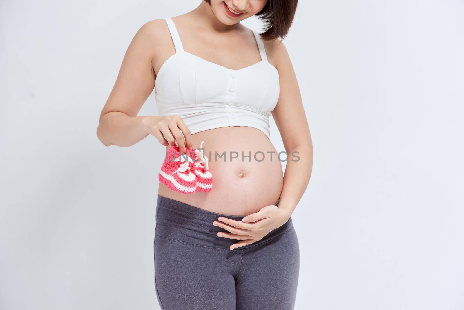 A portrait of a Pregnant woman with a pair of pink knit baby shoes