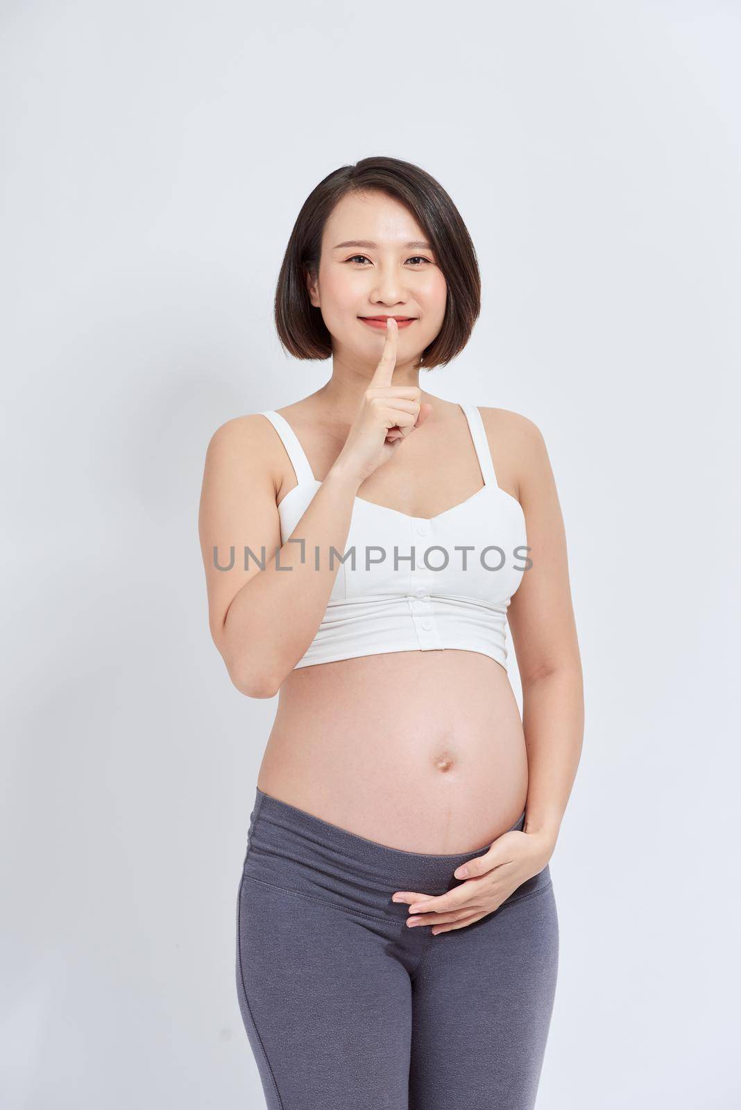 Young beautiful asian woman pregnant expecting baby asking to be quiet with finger on lips. silence and secret concept.
