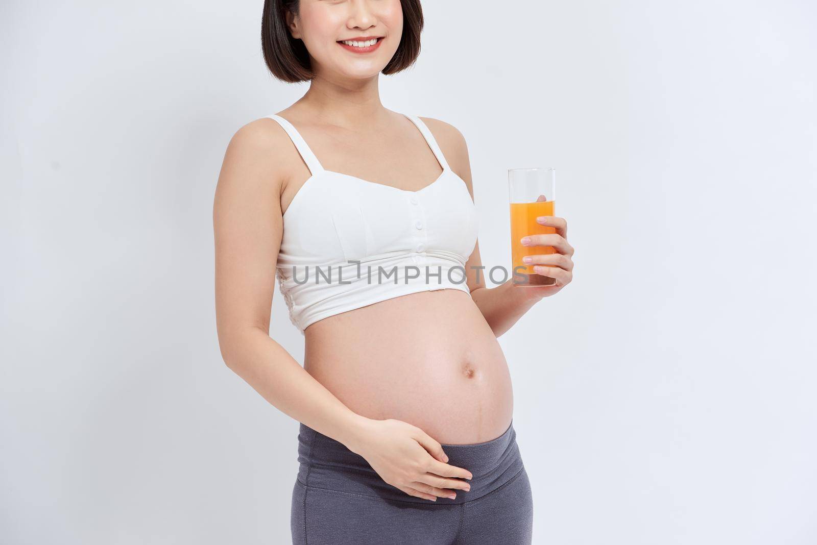 Young pregnant woman drinking orange juice with pleasure