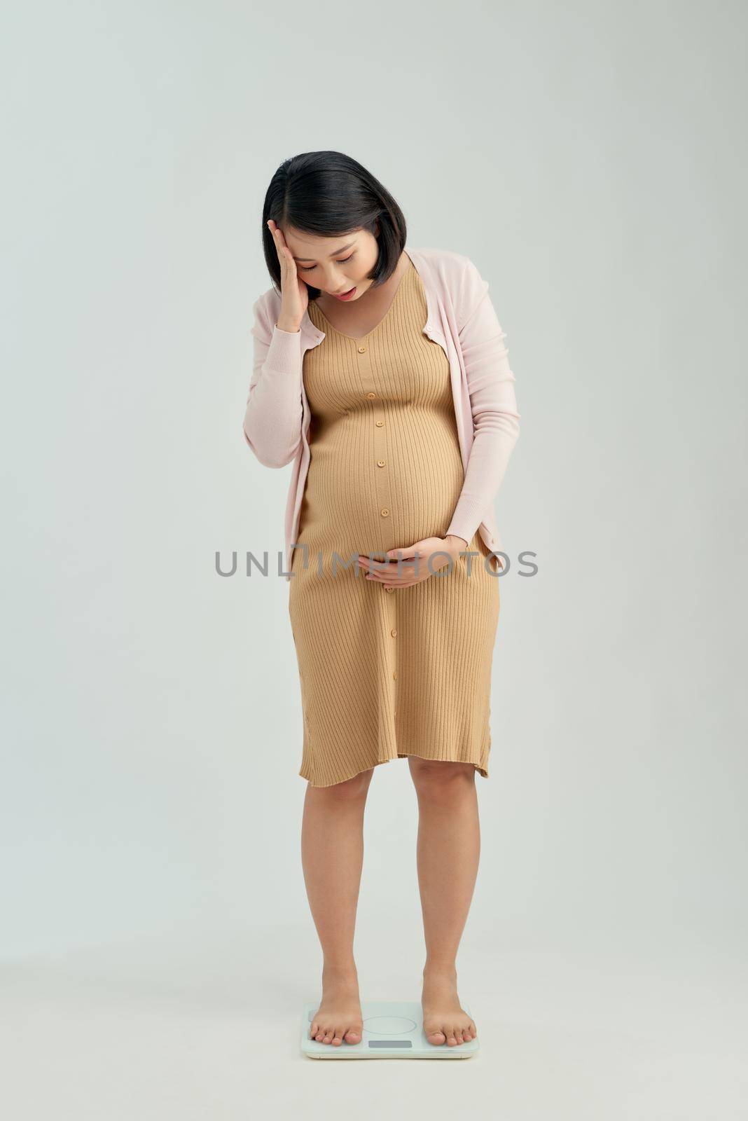 Pregnant woman standing on scales at home. Pregnancy weight gain concept by makidotvn