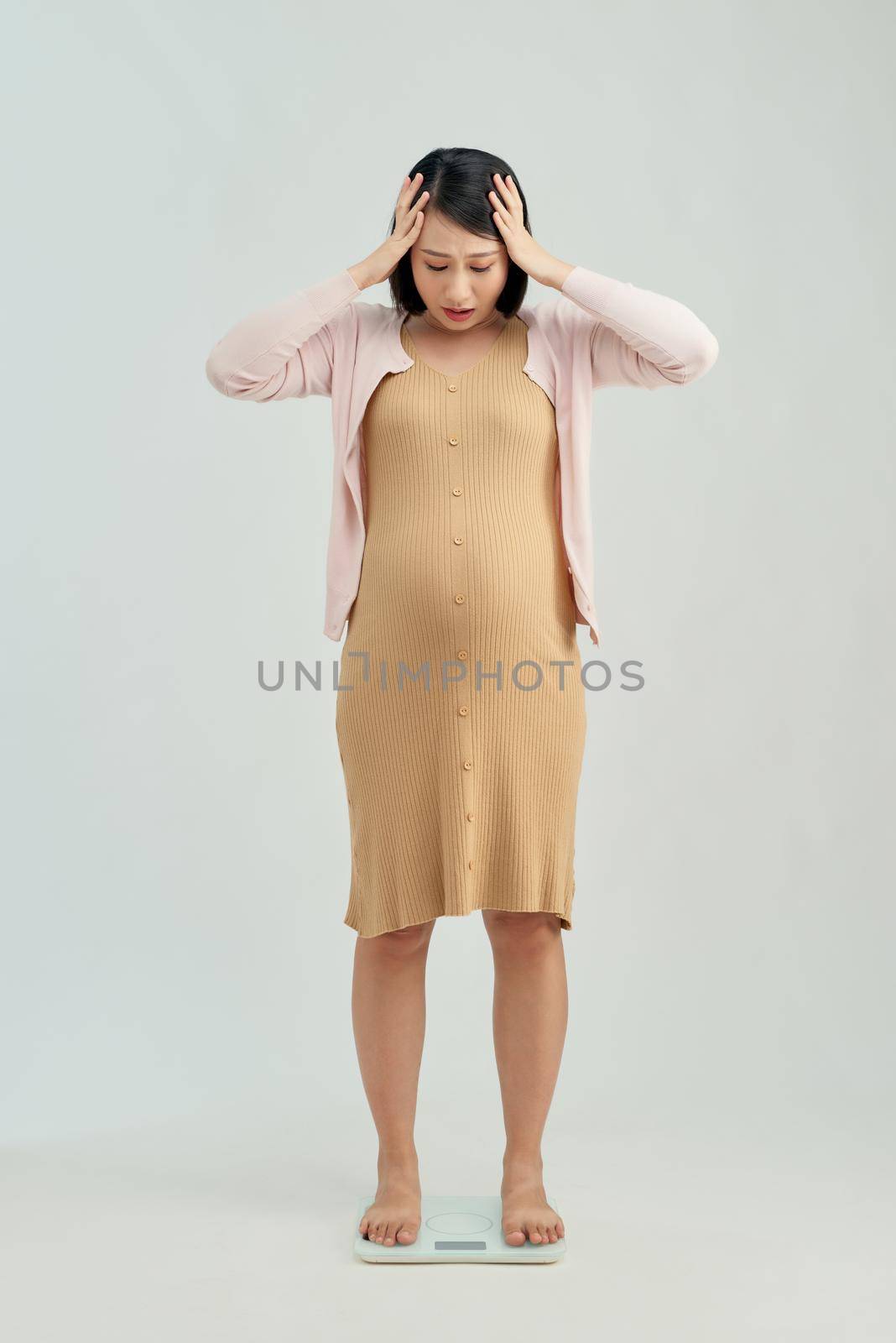 pregnant woman standing on a weight scale 