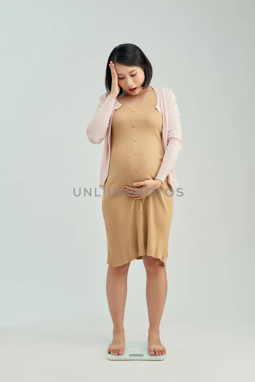 Pregnant woman standing on scales at home. Pregnancy weight gain concept by makidotvn