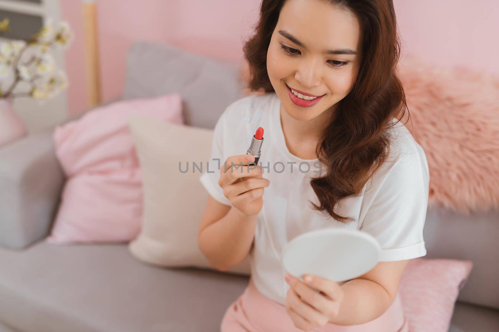 Asian woman beauty blogger, vlogger applying makeup lipstick, doing cosmetic makeup tutorial