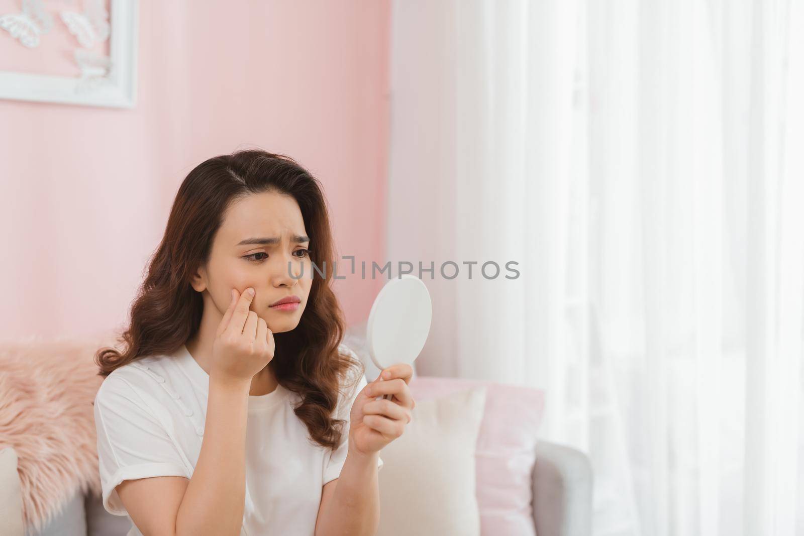 young woman squeezing pimples in front of mirror by makidotvn