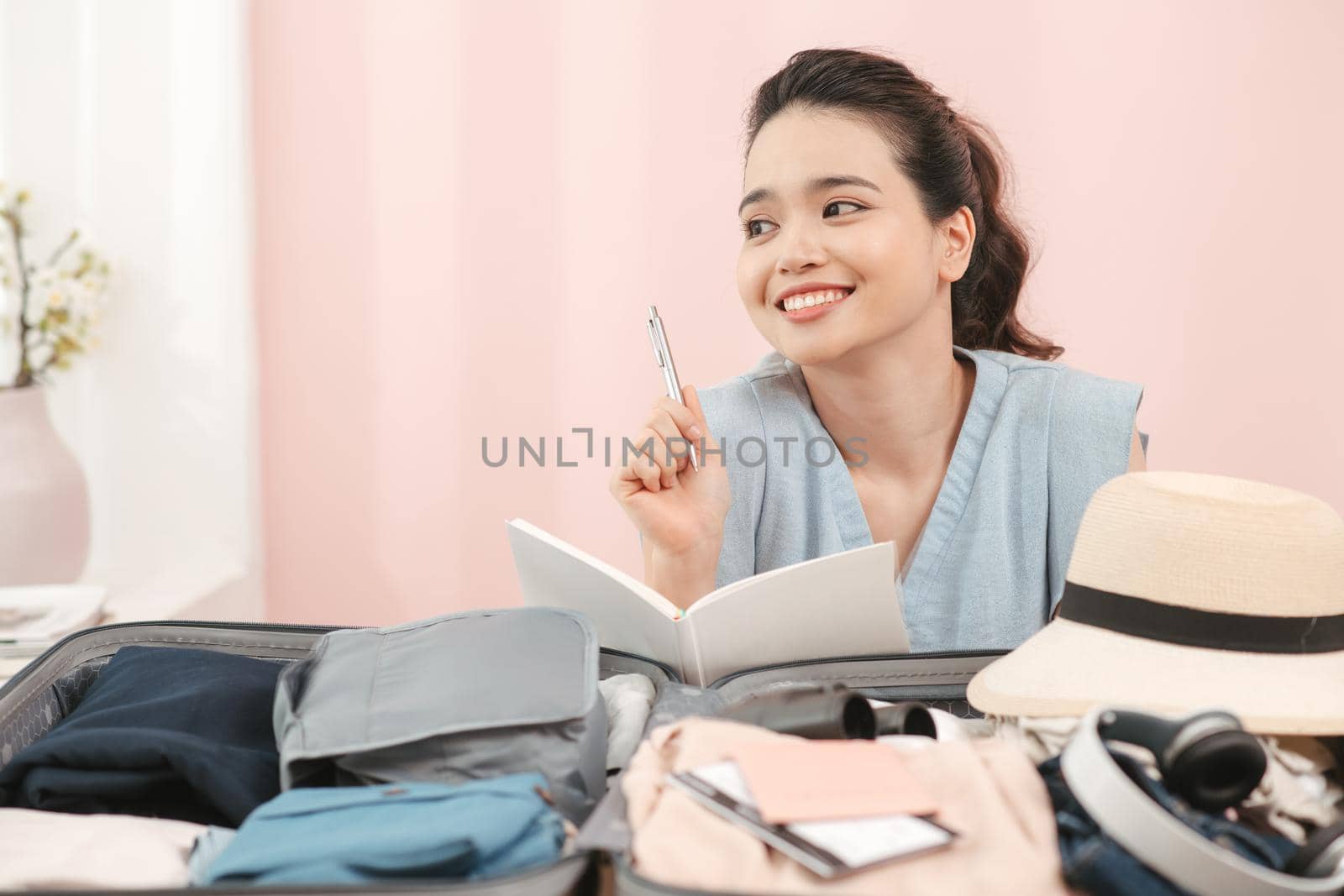 young asian pretty woman traveler smiling prepare and packing clothes into suitcase for holiday vacation at home