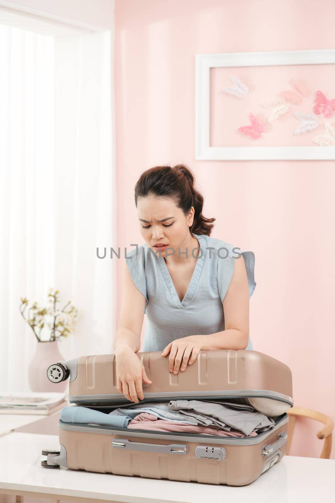 Woman prepare travel suitcase at home. Excited woman trying to close full suitcase.