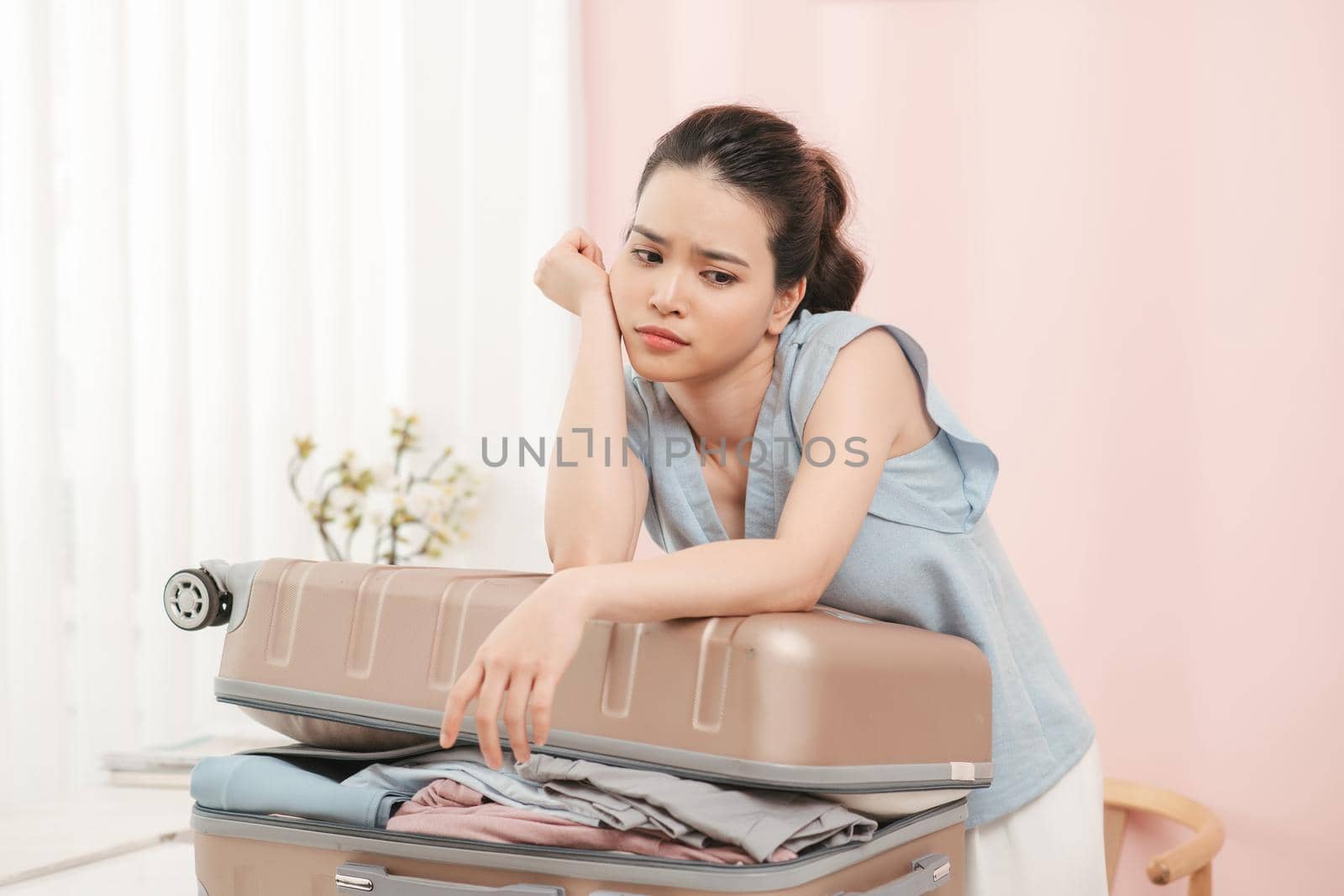 Girl packing for travel, closing hardly overflowing luggage bag.