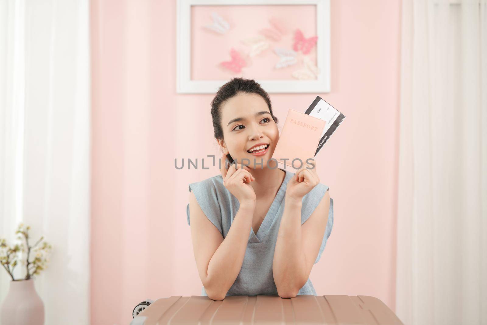 Happy woman holding passport, ready for travel with suitcase nearby