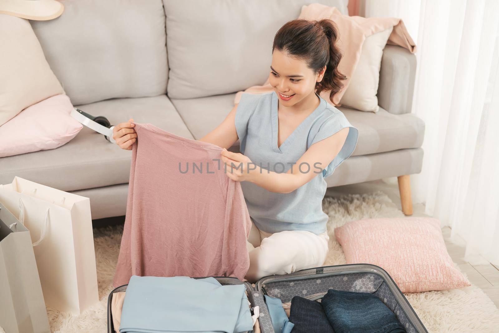 Young asian woman packing clothes into travel bag - Luggage and people concept