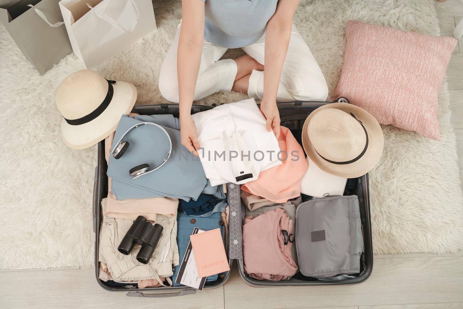 Passport in girl hand and travel accessories costumes, luggage, camera, clothes in suitcase, prepared for the trip and travel concept by makidotvn