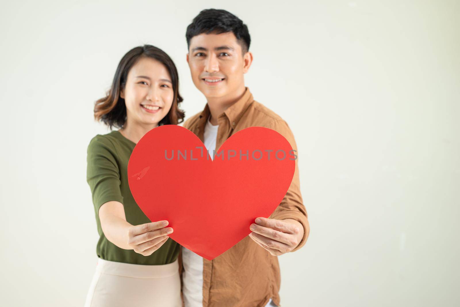 Young Asian couple holding a heart sticker