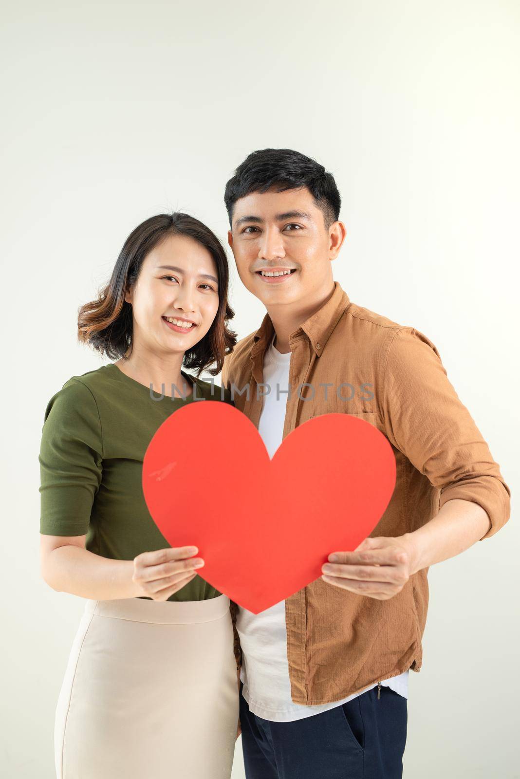 Happy young Asian couple holding heart shape over white background. by makidotvn