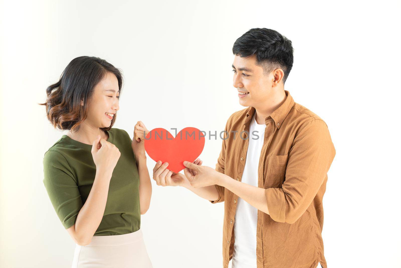 Smiling loving couple holding heart shape over white background.