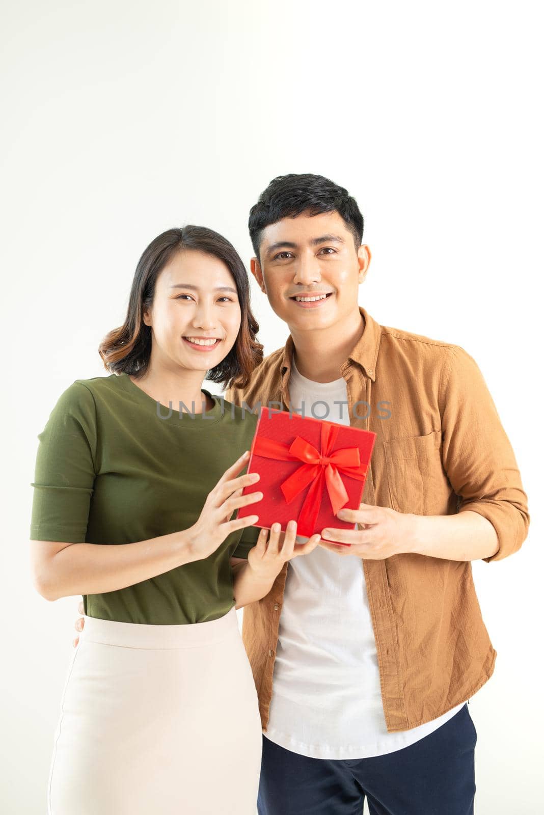 Portrait of happy couple in casual wear standing, holding box with present and looking at camera together